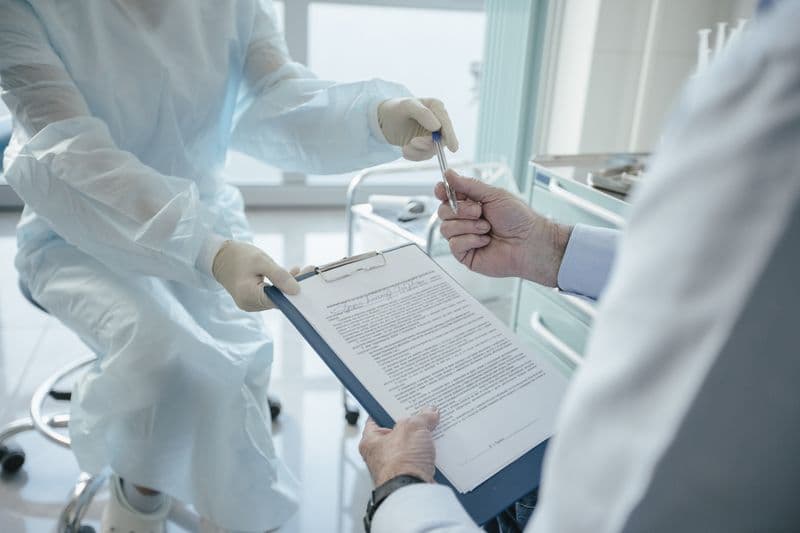 Doctor handing clipboard with aftercare instructions to patient — aesthetic clinic aftercare template guide