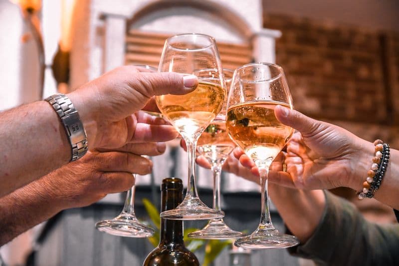 Friends toasting with white wine glasses indoors — how long after Botox can you drink alcohol guide