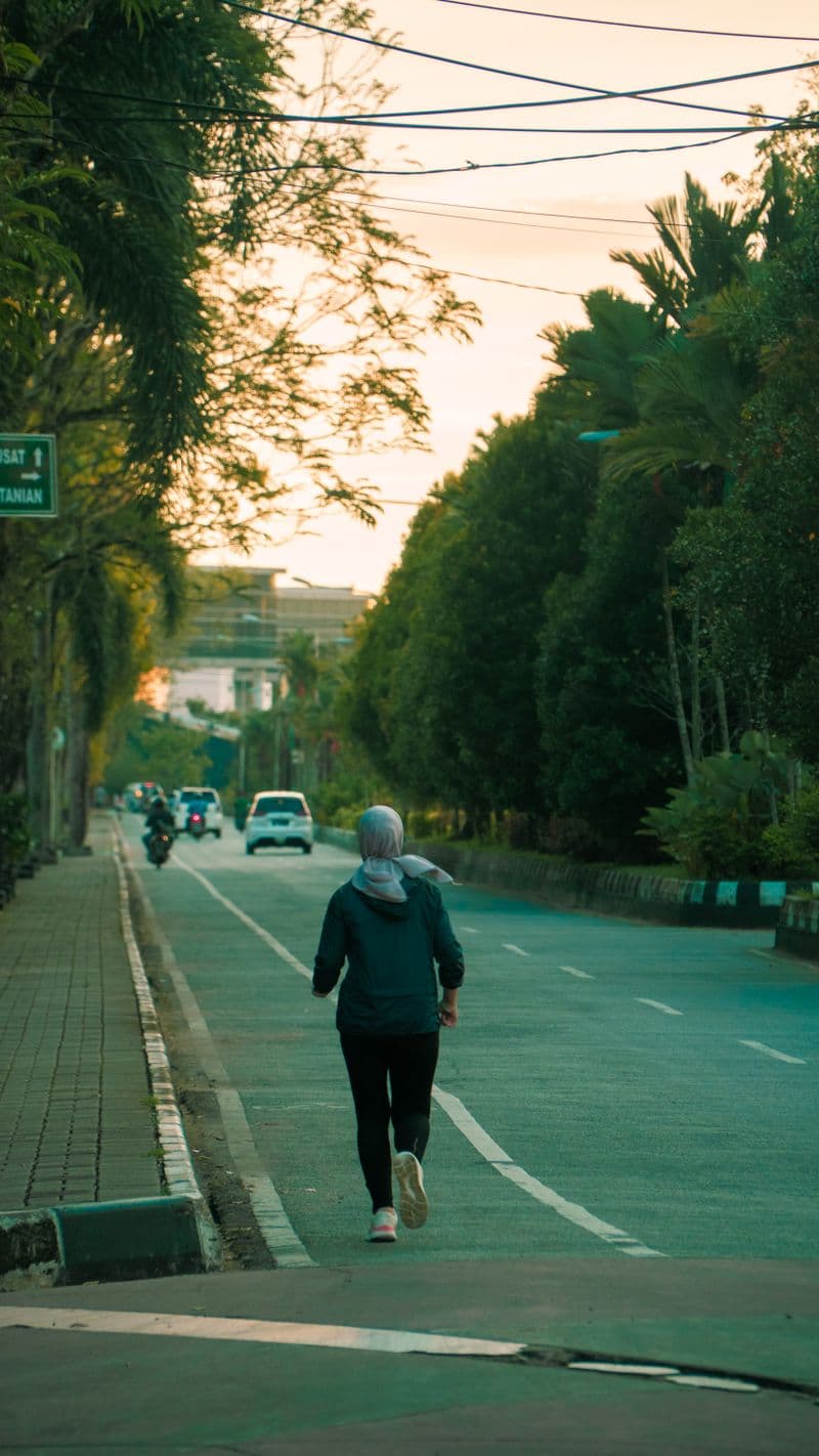 Woman jogging on tree-lined street at sunrise — how long after lip filler can you exercise guide