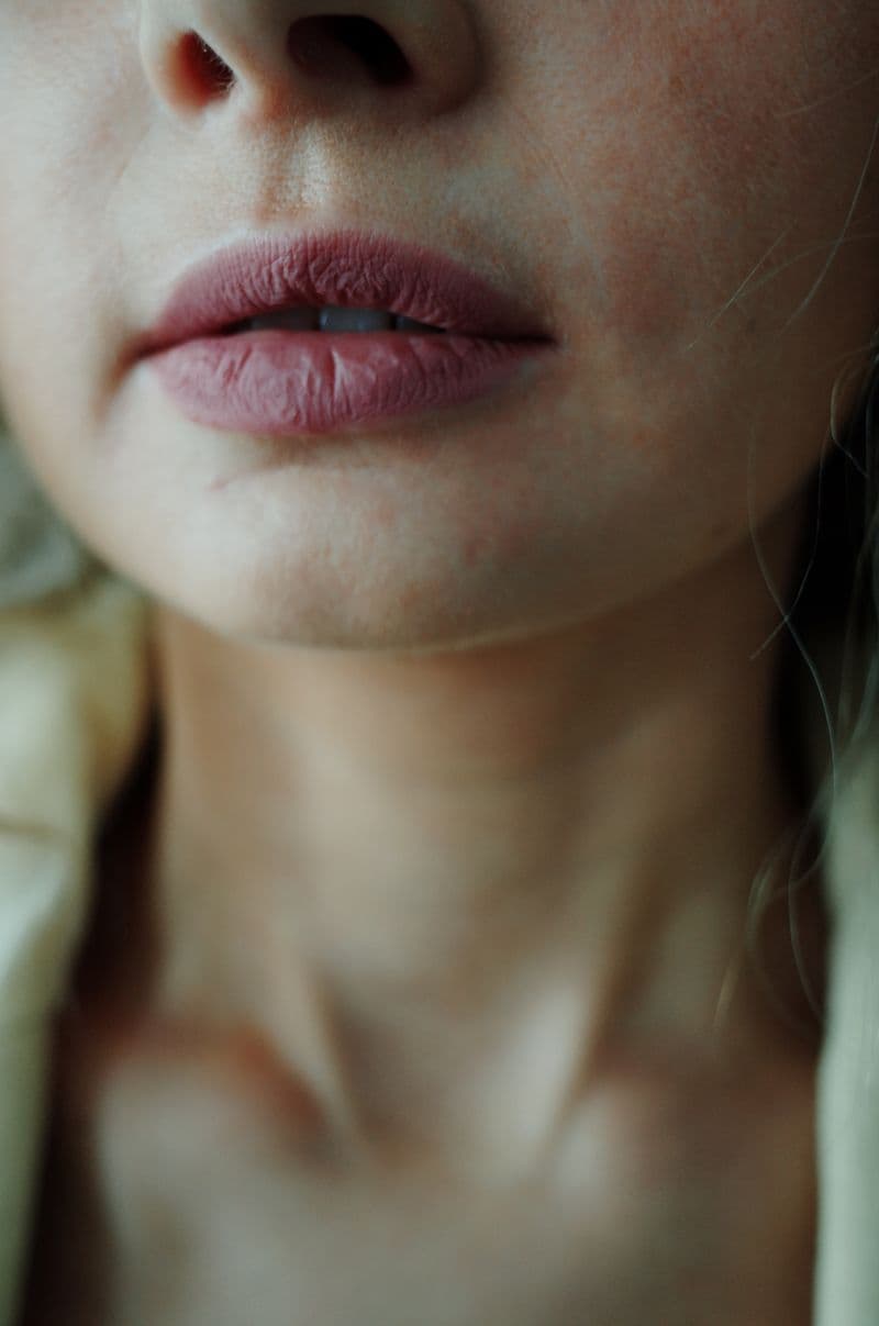 Artistic close-up of woman's lips and neck with soft lighting — lip filler migration signs and treatment guide