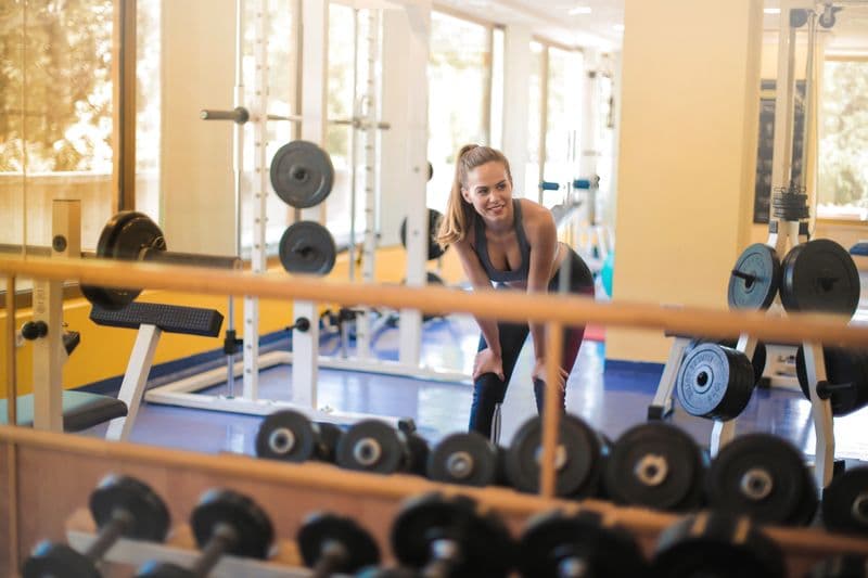 Fit woman in gym with weights — illustrating how long to wait before exercising after Botox