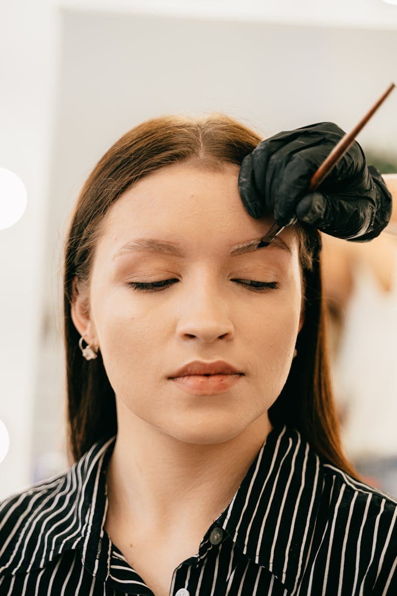 Woman undergoing precise eyebrow microblading treatment — microblading vs powder brows comparison guide