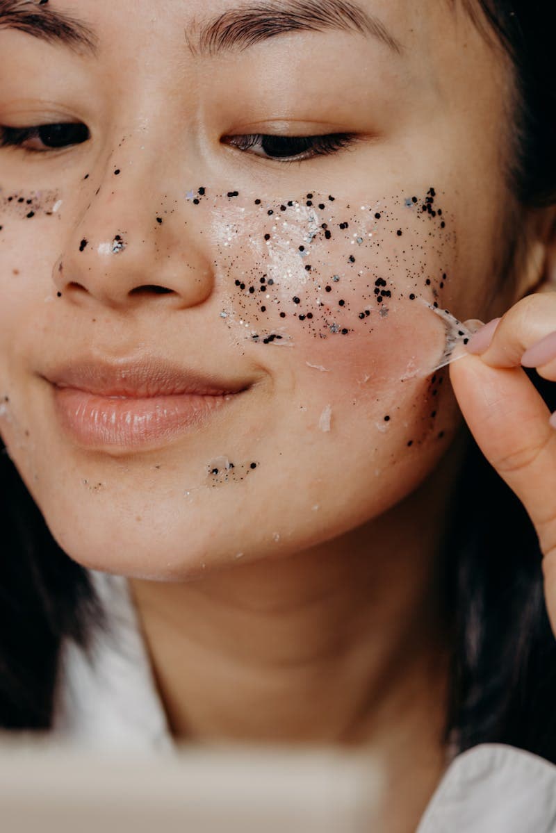 Woman carefully peeling off exfoliating face mask during skincare recovery — TCA peel aftercare guide
