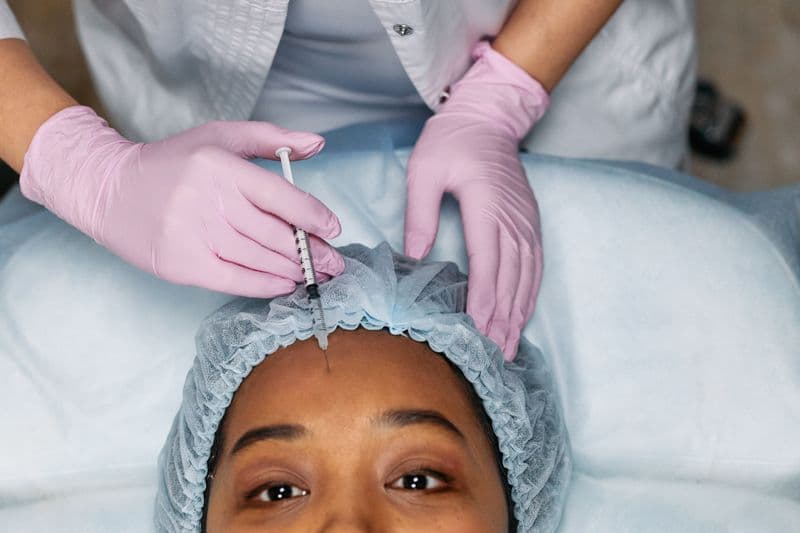 Botox injection being administered to woman's forehead in clinical setting — forehead vs glabella guide