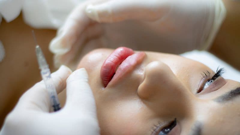 Close-up of woman receiving lip injection treatment from professional — Botox lip flip aftercare guide